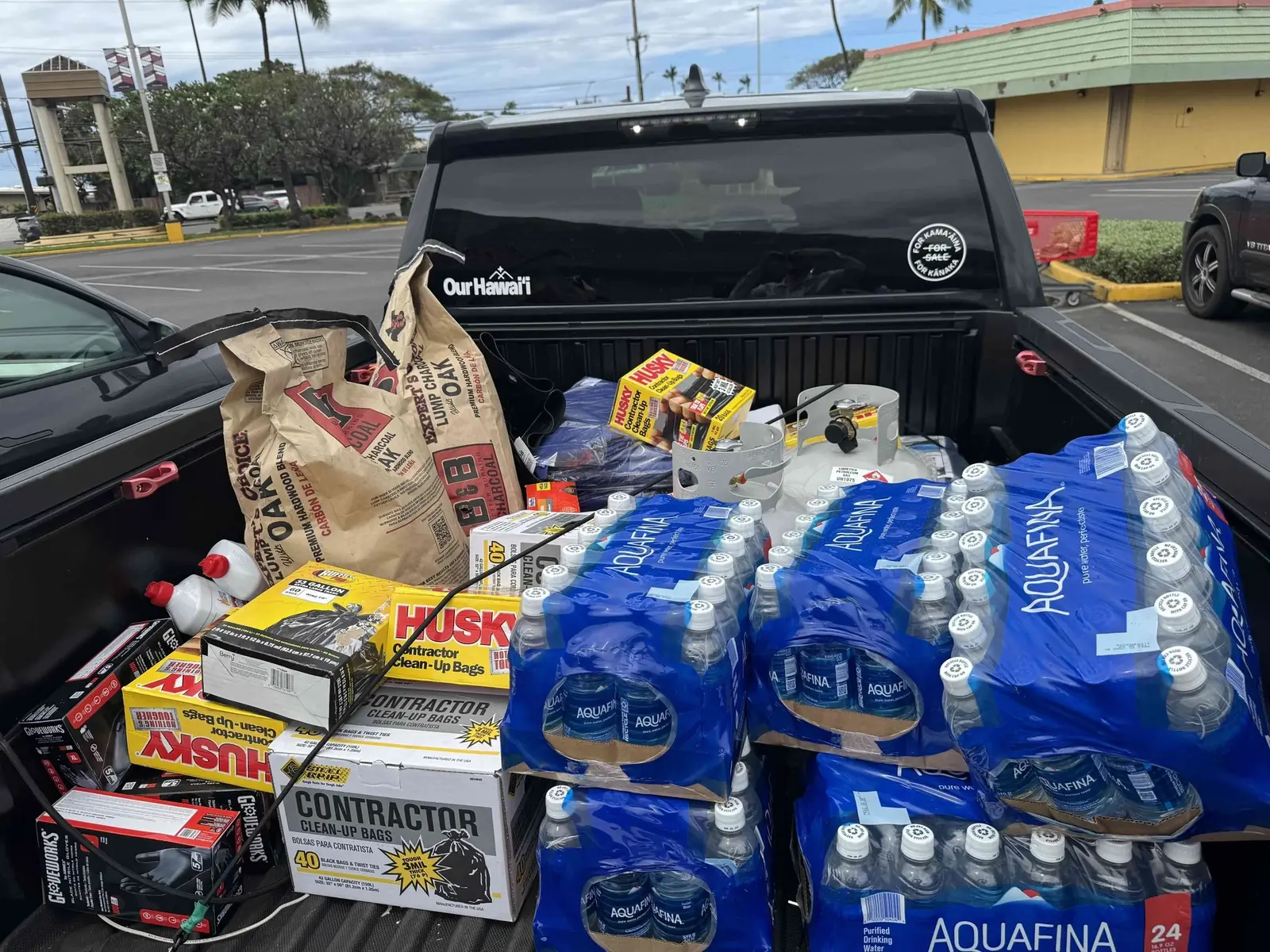 A pickup truck bed packed with bottled water, food and cleanup supplies
