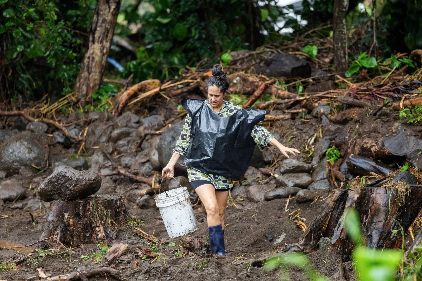 A volunteer hauling buckets of mud out of a flooded yard